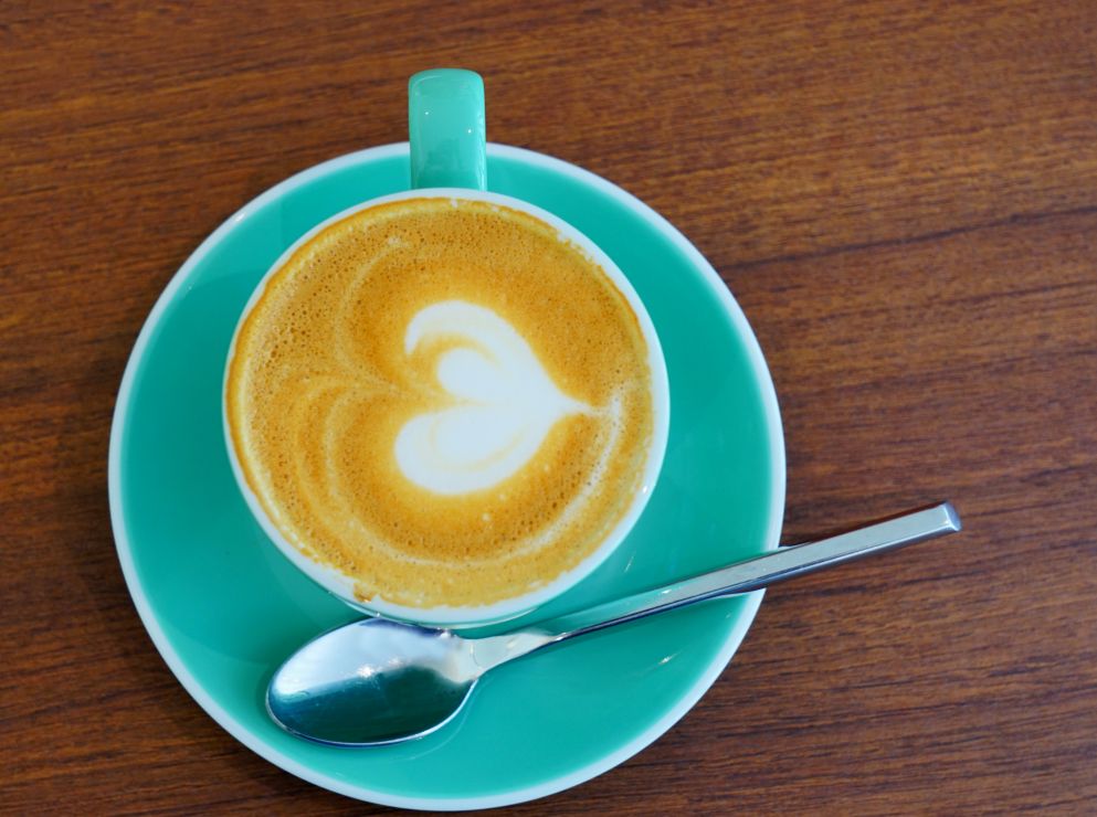 une tasse de café sur une soucoupe avec une cuillère. . main tiré